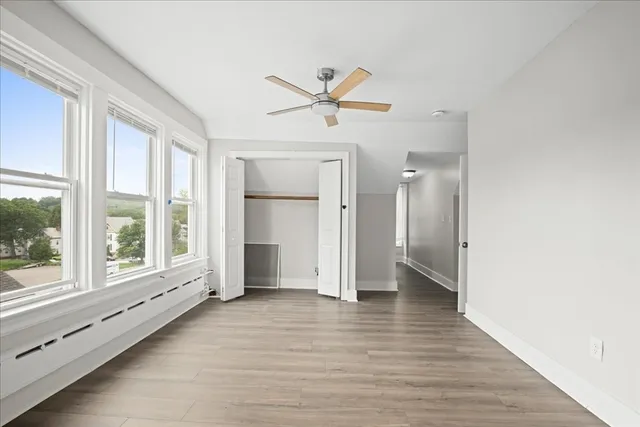 a view of an empty room with wooden floor and a window