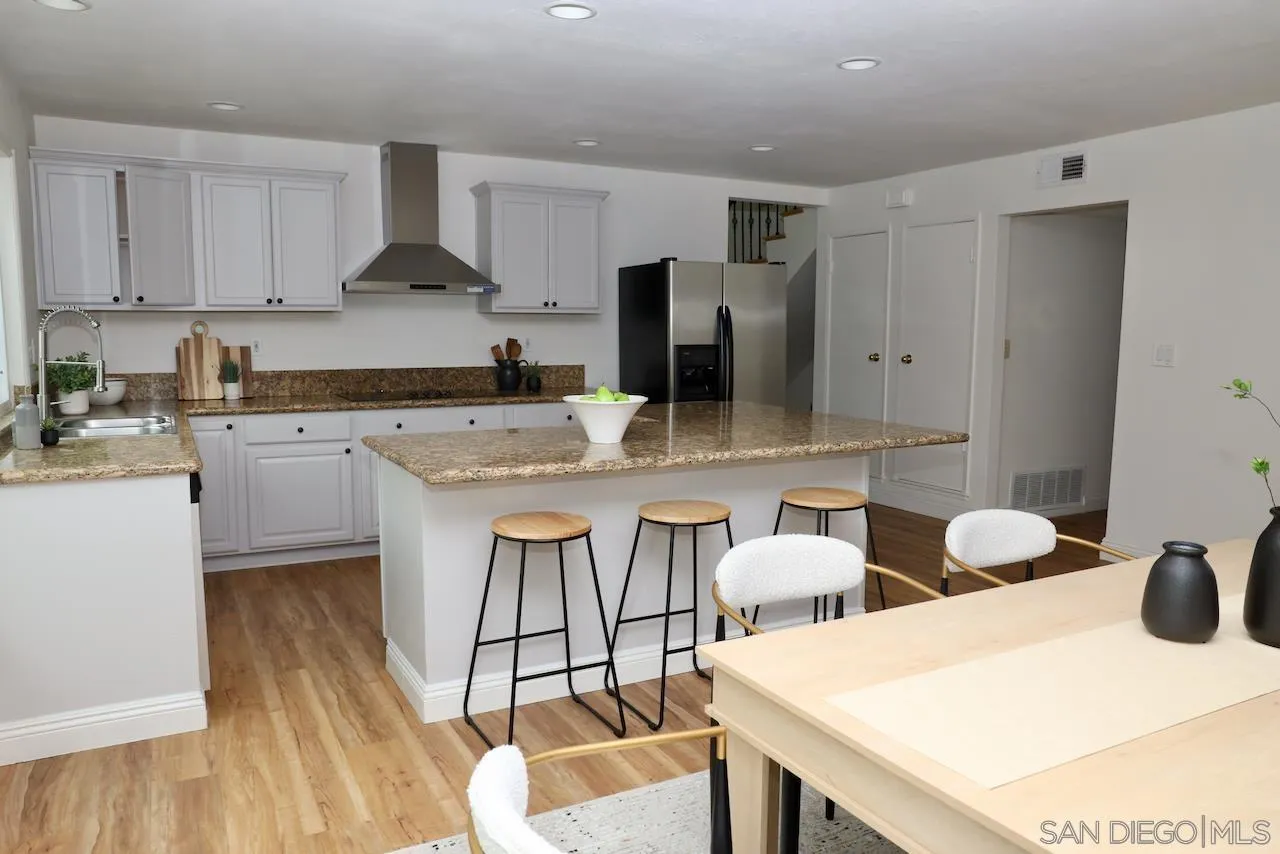 8907 Taurus Place San Diego, CA 92126 - Photo 12 of 40 a kitchen with stainless steel appliances kitchen island granite countertop a sink a stove a refrigerator and white cabinets with wooden floor