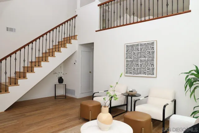 a living room with couches with wooden floor and windows