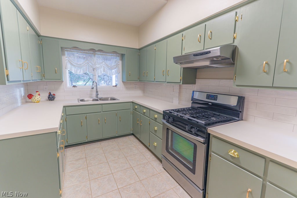 51883 Telegraph Road Amherst, OH 44001 - Photo 5 of 49 Kitchen featuring backsplash, stainless steel gas range, light tile patterned floors, green cabinets, and sink