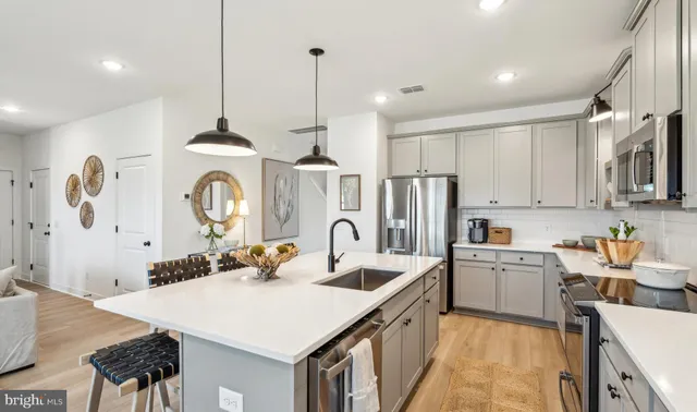 a kitchen with stainless steel appliances a sink a stove a refrigerator cabinets and living room view