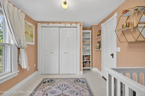 a view of a bedroom with wooden floor & a window