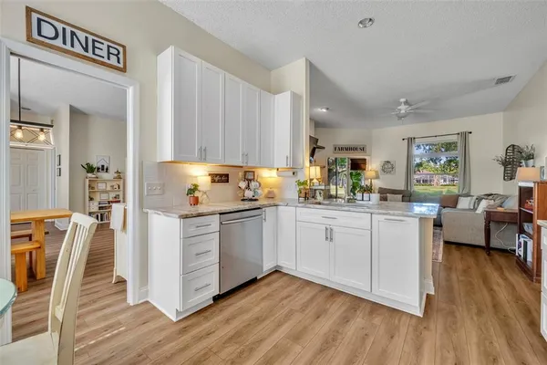 a kitchen with stainless steel appliances granite countertop a refrigerator a sink dishwasher and white cabinets with wooden floor