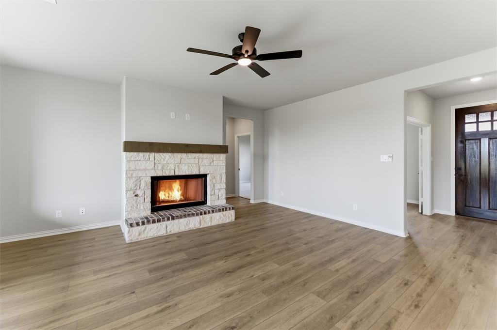 137 Moss Gln Lane Rhome, TX 76078 - Photo 11 of 25 a view of an empty room with wooden floor fireplace and a window