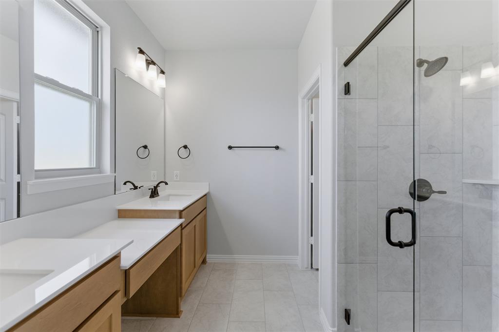137 Moss Gln Lane Rhome, TX 76078 - Photo 16 of 25 a bathroom with a double vanity sink a mirror and a shower