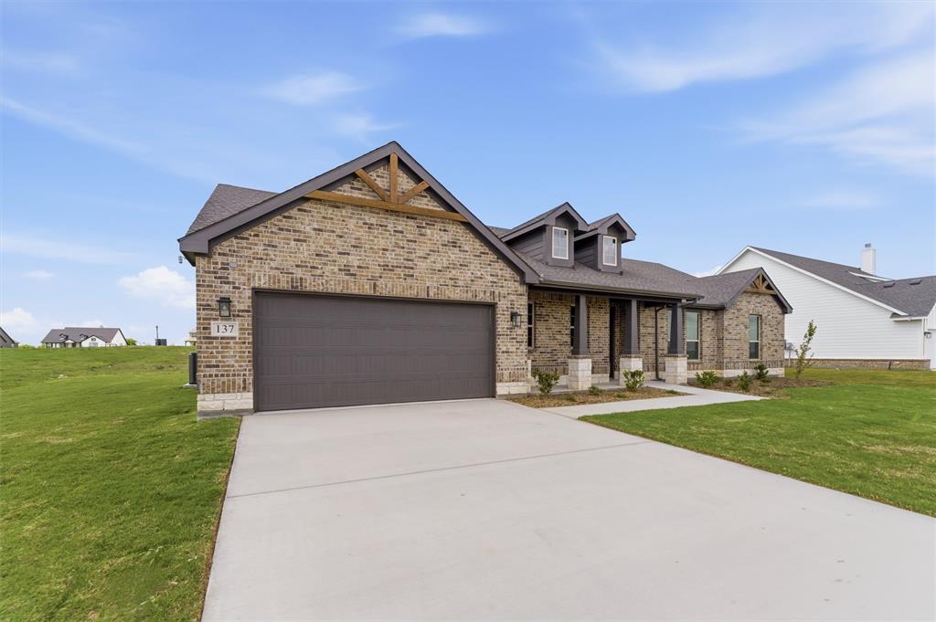 137 Moss Gln Lane Rhome, TX 76078 - Photo 4 of 25 a front view of a house with a yard and garage