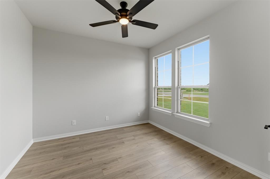 137 Moss Gln Lane Rhome, TX 76078 - Photo 6 of 25 an empty room with wooden floor fan and windows