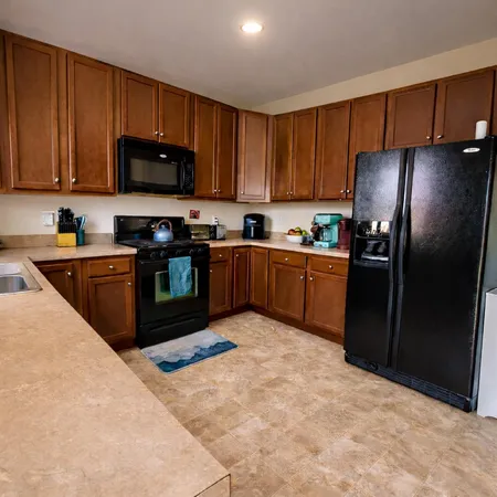 a kitchen with stainless steel appliances granite countertop a stove top oven a refrigerator and a sink