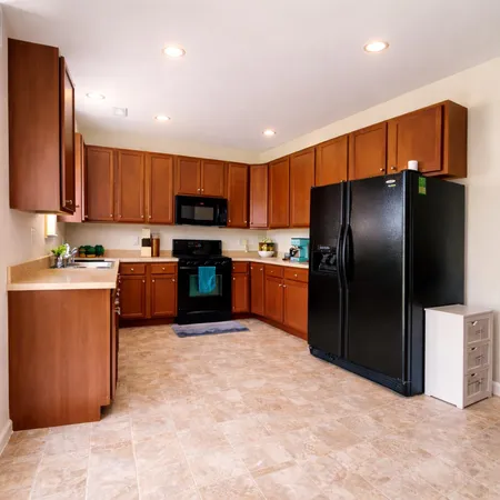 a kitchen with stainless steel appliances granite countertop a refrigerator a stove top oven and a sink