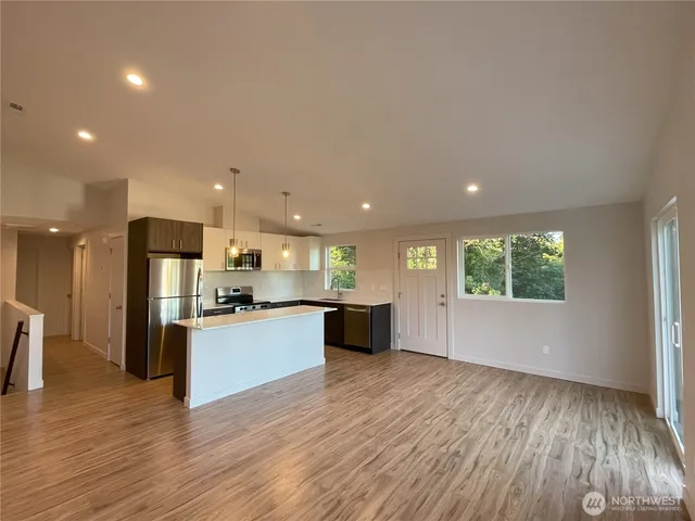 a large kitchen with stainless steel appliances kitchen island granite countertop a large counter top and a wooden floors