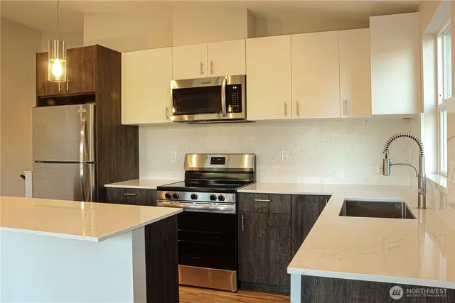 a kitchen with stainless steel appliances granite countertop a sink a stove a microwave a refrigerator a stove and white cabinets