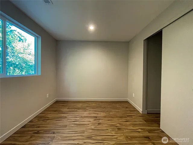 a view of an empty room with wooden floor and a window