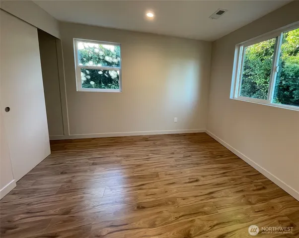 an empty room with wooden floor and windows