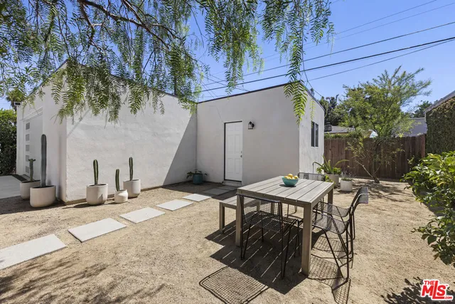 a backyard of a house with table and chairs and potted plants