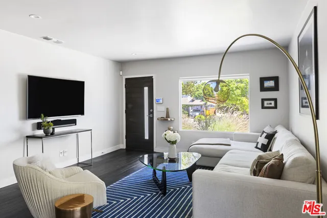 a living room with furniture a flat screen tv and a large window