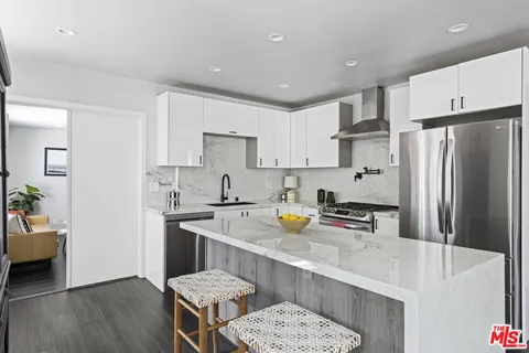 a kitchen with stainless steel appliances a refrigerator a sink a stove a table and chairs
