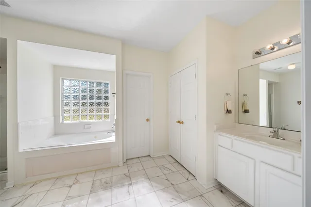 a spacious bathroom with a granite countertop sink a mirror and a bathtub