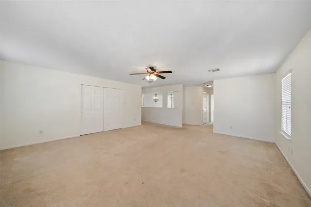 an empty room with chandelier fan and windows