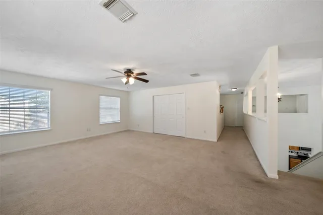 an empty room with windows and ceiling fan
