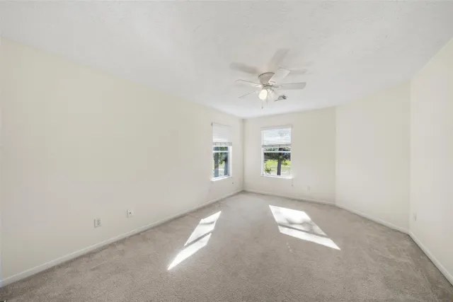 an empty room with a window and a ceiling fan
