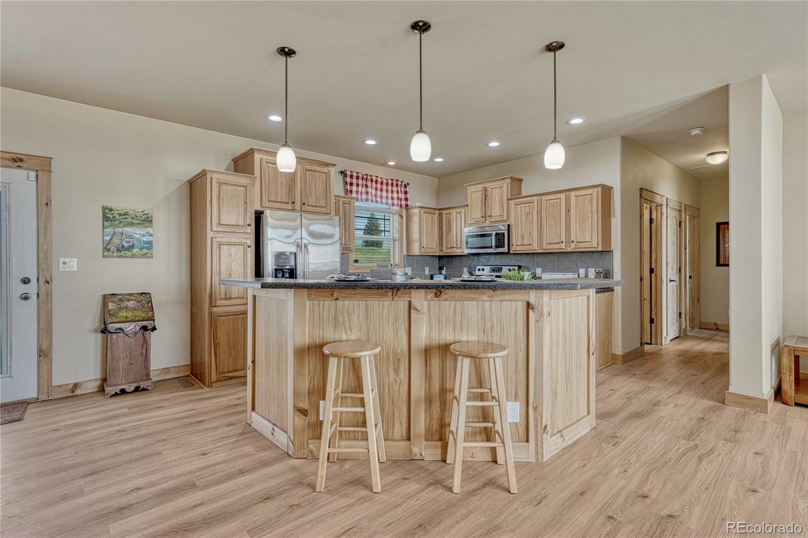 17355 Wagon Train Loop Peyton, CO 80831 - Photo 8 of 48 a kitchen with stainless steel appliances granite countertop a refrigerator a oven and a wooden floors