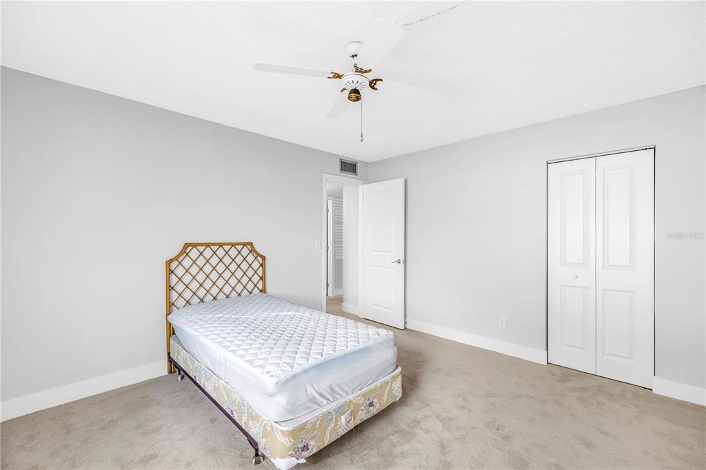 4700 Cove Circle, Unit 103 St. Petersburg, FL 33708 - Photo 26 of 31 a bedroom with a bed and a ceiling fan