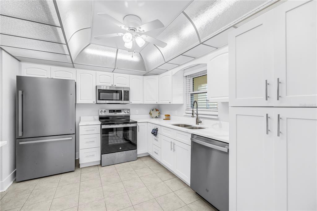 4700 Cove Circle, Unit 103 St. Petersburg, FL 33708 - Photo 7 of 31 a kitchen with stainless steel appliances granite countertop a refrigerator a sink dishwasher a stove and white cabinets