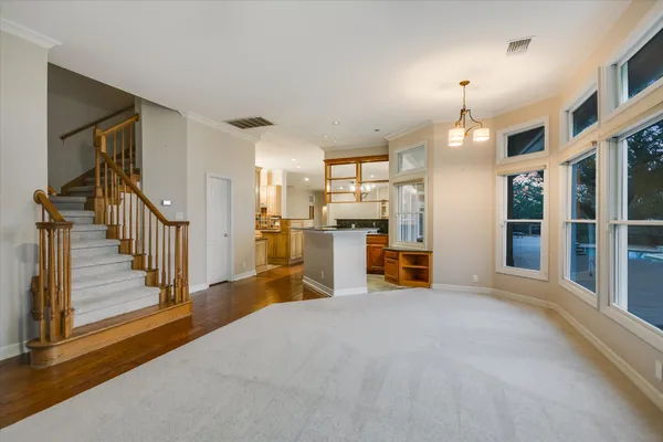 a view of an empty room with a window and kitchen view