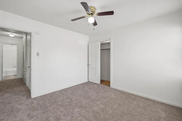 an empty room with closet and a ceiling fan