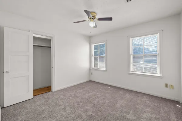 an empty room with windows and a ceiling fan