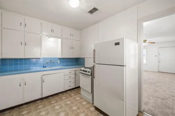 a kitchen with white cabinets and refrigerator