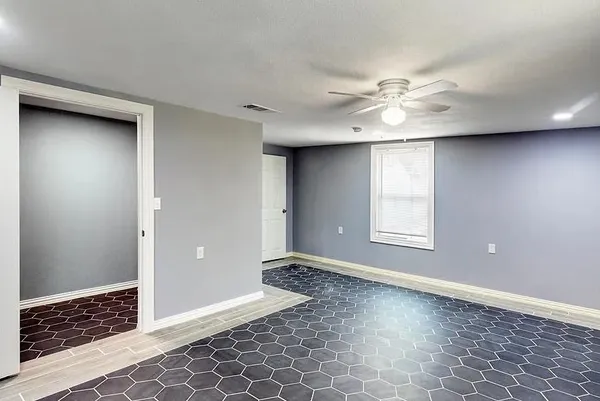 an empty room with windows and fan