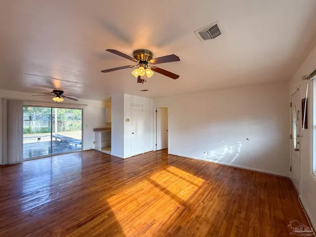 a view of empty room with wooden floor and fan