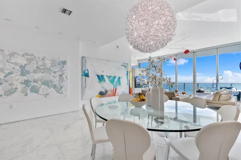 a kitchen with stainless steel appliances kitchen island granite countertop a table chairs in it and white cabinets