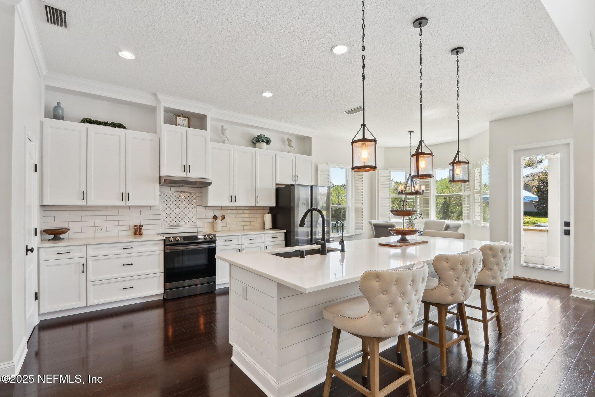 212 Cornwall Drive Ponte Vedra, FL 32081 - Photo 15 of 84 a kitchen with stainless steel appliances kitchen island granite countertop a stove a sink and white cabinets with wooden floor