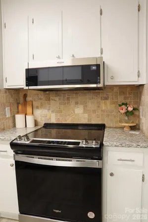 a kitchen with stainless steel appliances granite countertop a stove a sink and white cabinets