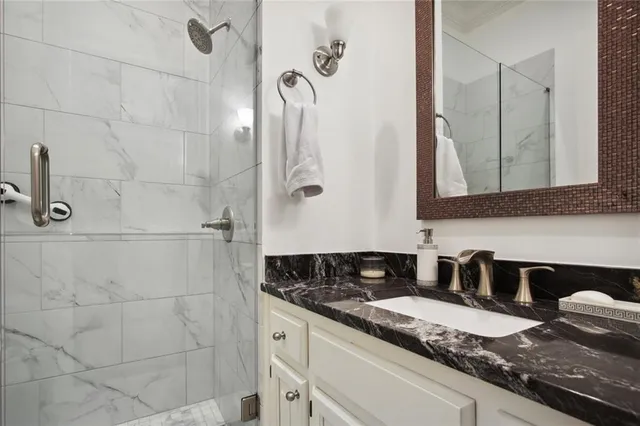 a bathroom with a granite countertop sink a mirror and shower