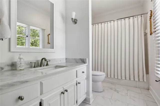 a bathroom with a granite countertop sink a toilet and a mirror