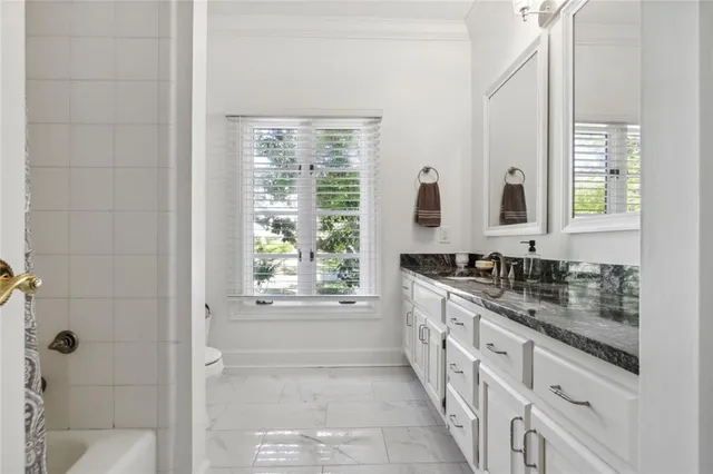 a bathroom with a granite countertop sink a mirror and a bathtub