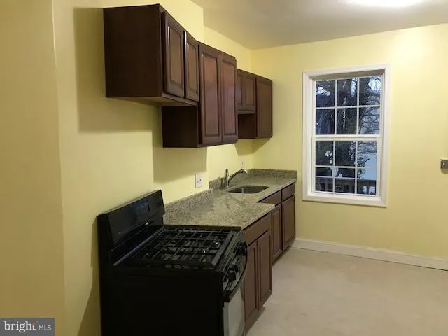 a kitchen with granite countertop a stove and a sink