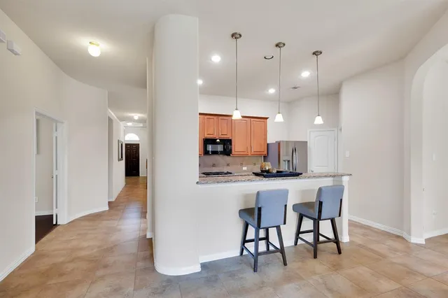 a view of a kitchen with kitchen island a dining table chairs stainless steel appliances and cabinets