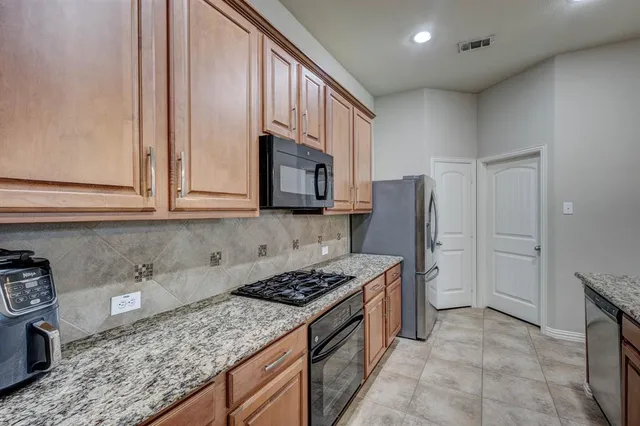 a kitchen with stainless steel appliances granite countertop a stove a sink and a microwave