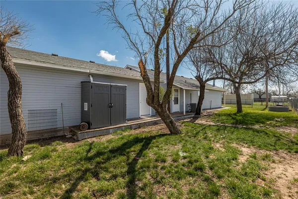 a backyard of a house with plants and large tree