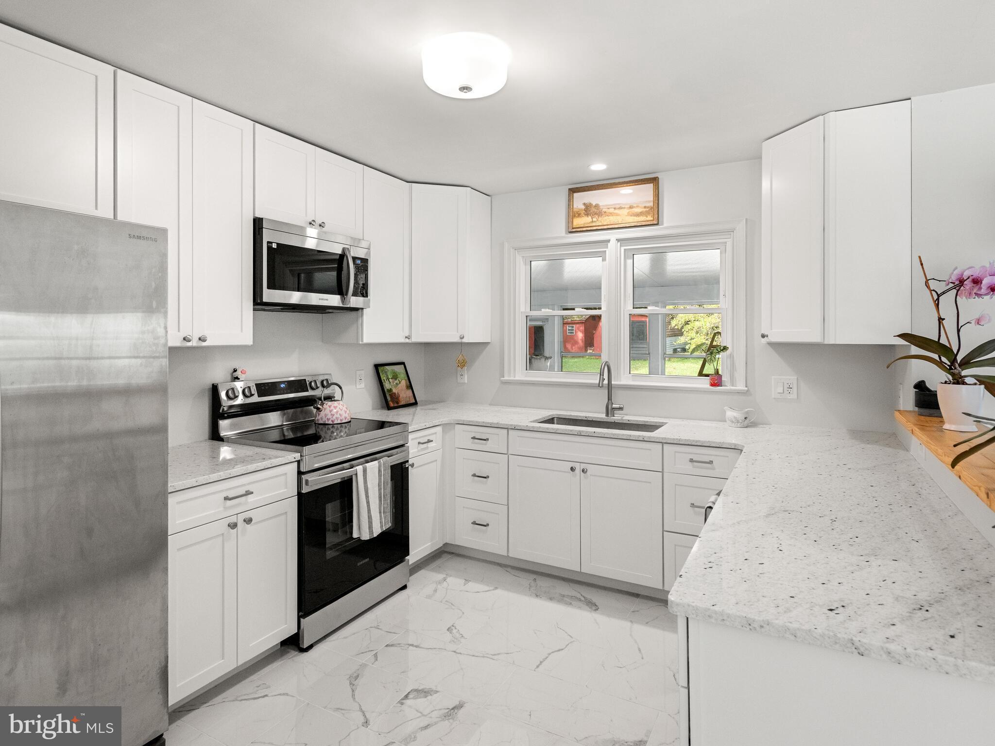 191 West Street Road Kennett Square, PA 19348 - Photo 7 of 41 a kitchen with stainless steel appliances granite countertop a stove top oven a sink a window and white cabinets