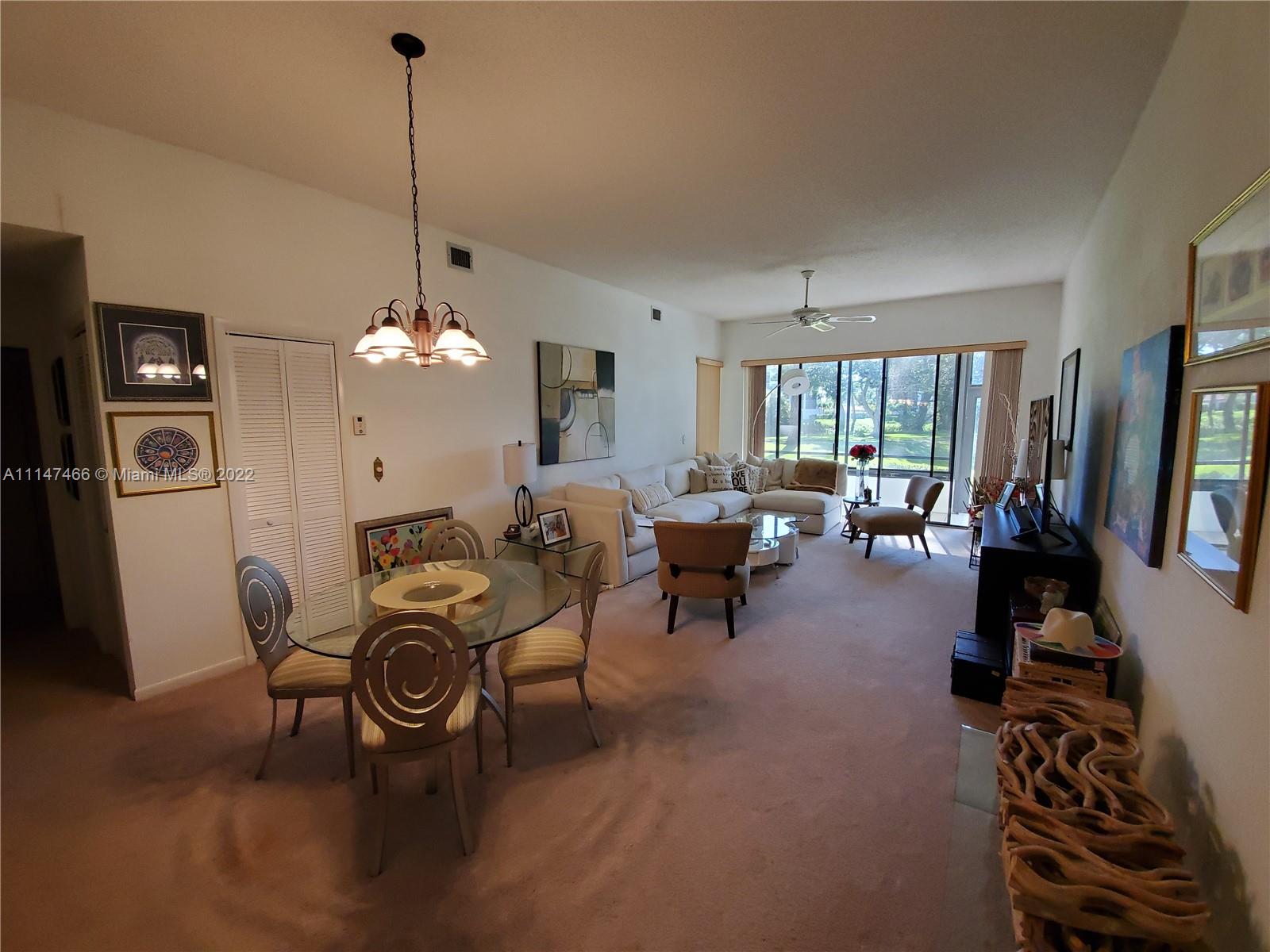 7472 La Paz Boulevard, Unit 104 Boca Raton, FL 33433 - Photo 13 of 44 a living room with furniture a chandelier and a flat screen tv