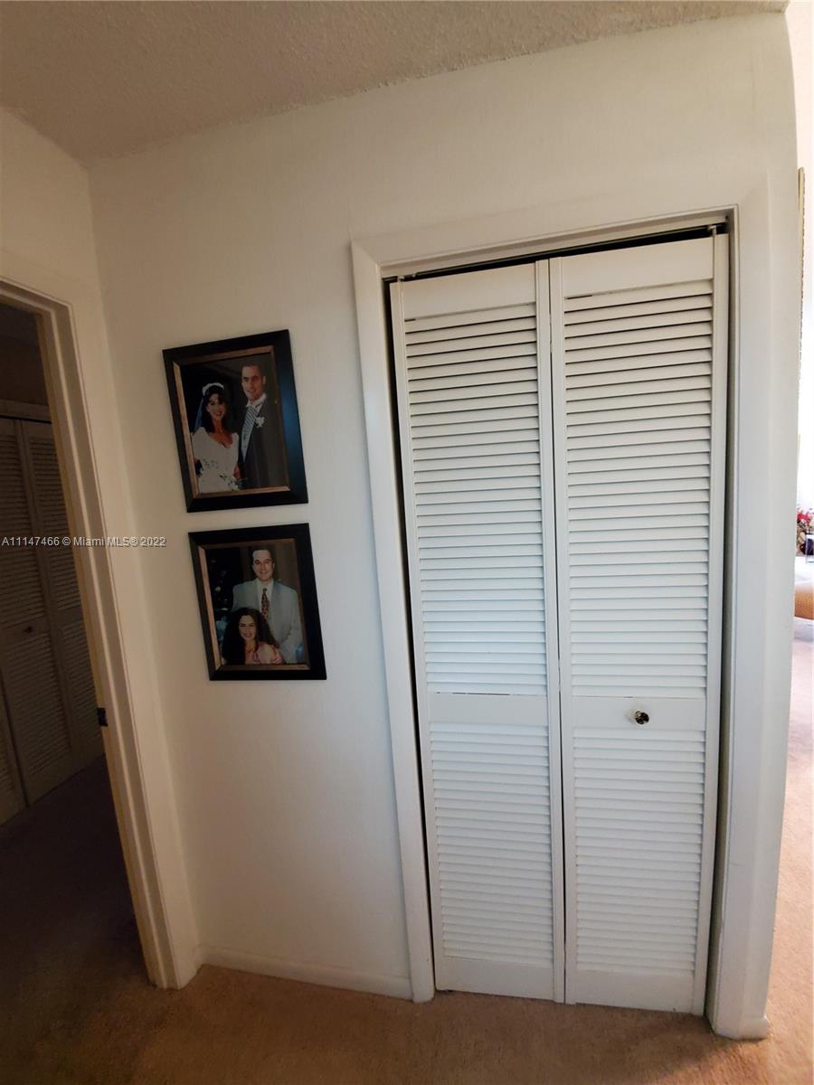 7472 La Paz Boulevard, Unit 104 Boca Raton, FL 33433 - Photo 28 of 44 a view of a hallway with wooden floor and white walls