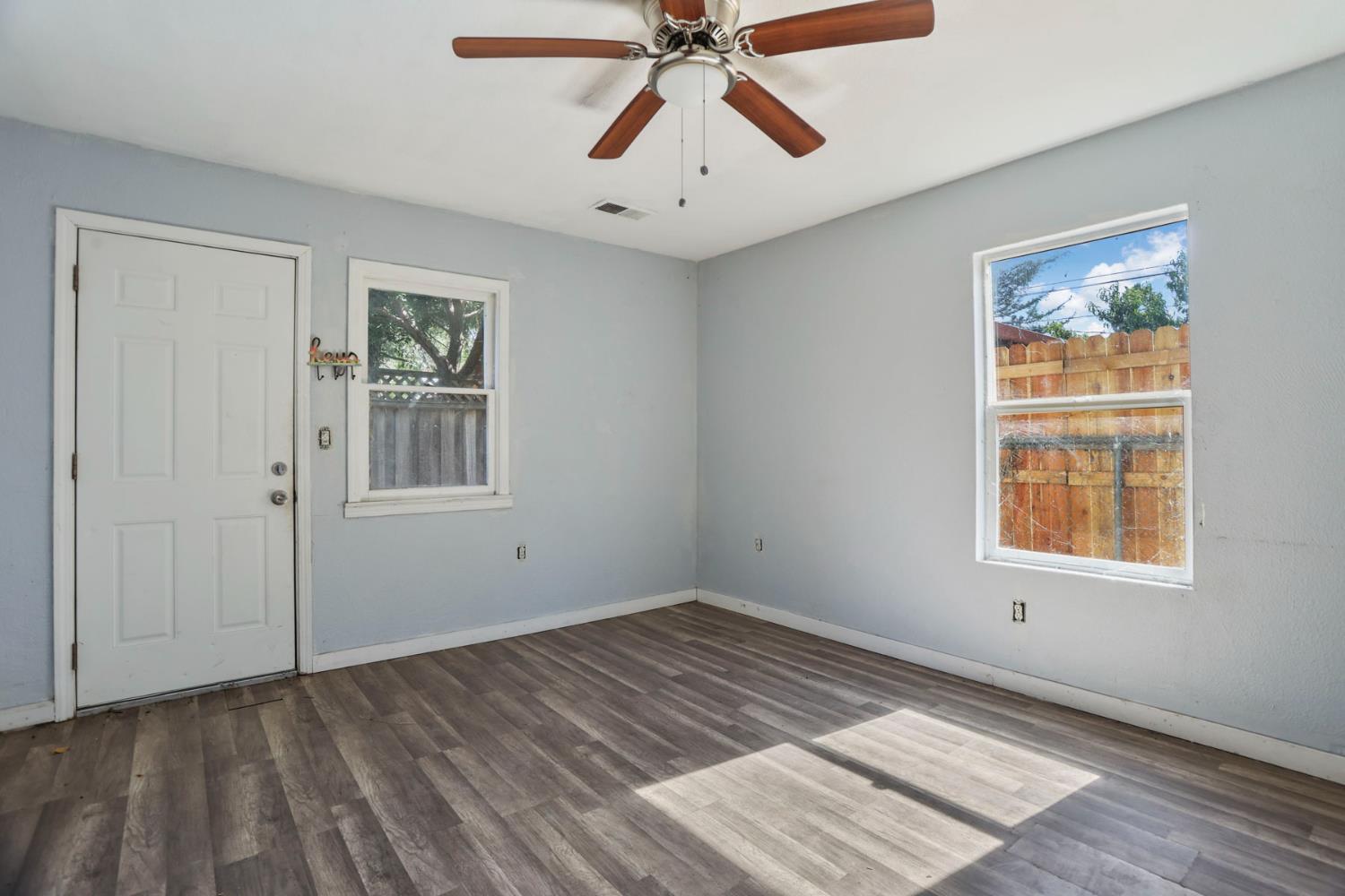 916 Elm Avenue Modesto, CA 95351 - Photo 37 of 52 Rear dwelling living space with ceiling fan, multiple windows, wood-look flooring, and functional room layout.