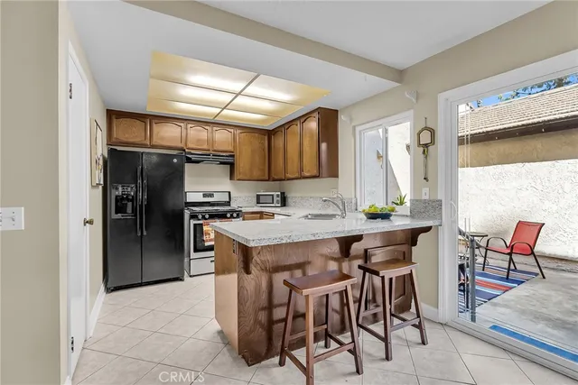 a kitchen with stainless steel appliances kitchen island granite countertop a table chairs and a refrigerator
