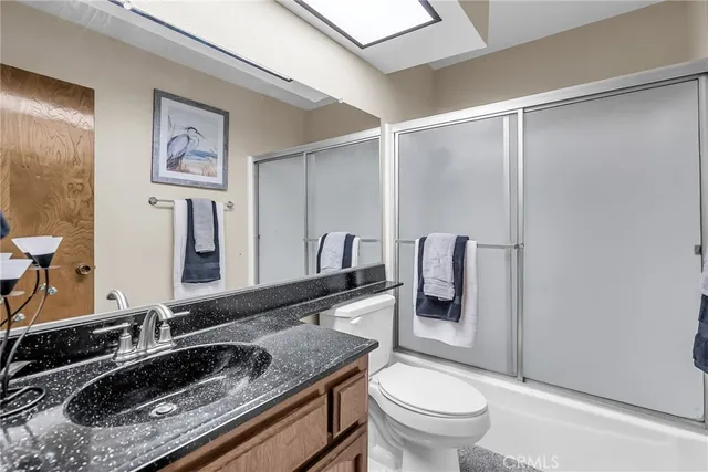 a bathroom with a granite countertop sink a toilet and a mirror