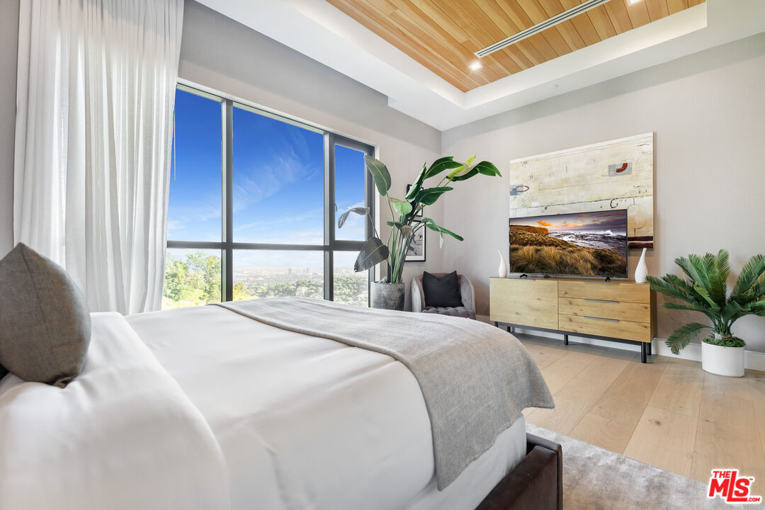 1033 Somera Road Los Angeles, CA 90077 - Photo 52 of 72 a bedroom with a large bed and a potted plant